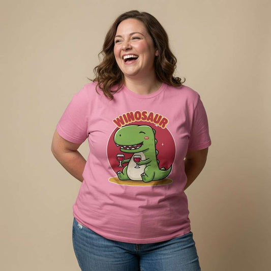 Woman laughing with both hands behind her back while wearing a pink Winosaur t-shirt featuring a cartoon dinosaur holding two glasses of wine, ladies funny wine-obsessed design