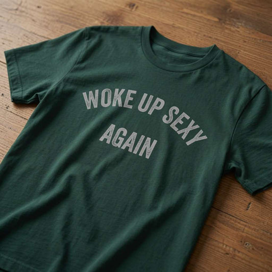 Green Woke Up Sexy Again t-shirt laid flat on a wooden surface showing the arched slogan, funny witty mens dad slogan design full of pure attitude