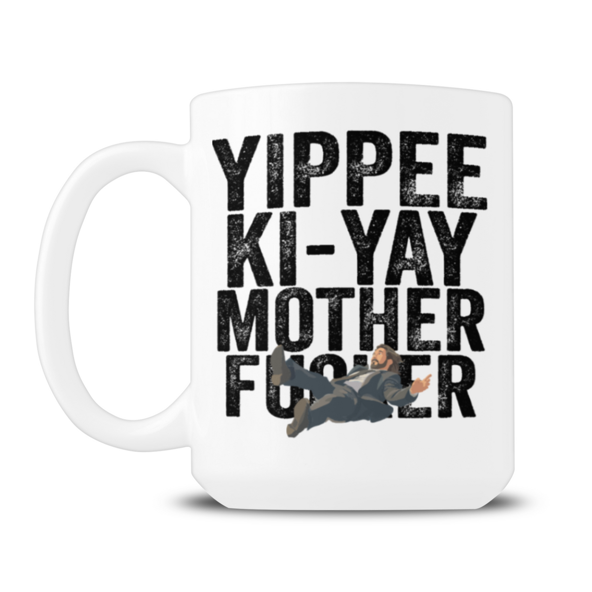 White mug features bold black text reading “Yippee-ki-yay motherf—er” with a small illustrated action hero sprawled across the lettering, creating a cheeky, irreverent tone.