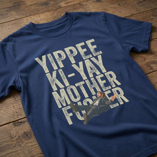 Blue Yippee Ki-Yay Mother Fucker t-shirt laid flat on a wooden surface showing the full falling McClane graphic, fun witty mens Xmas party design that every cheeky lad will claim