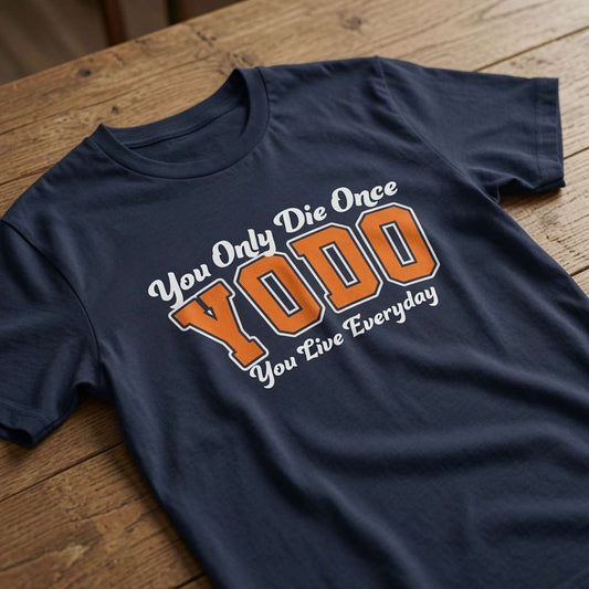 Navy YODO t-shirt laid flat on a wooden surface showing the full You Only Die Once / You Live Everyday slogan, fun alternative motivational slogan design that every no-nonsense lady will claim
