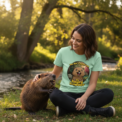Woman wearing a t-shirt with an angry beaver graphic sitting next to a beaver in a natural setting.