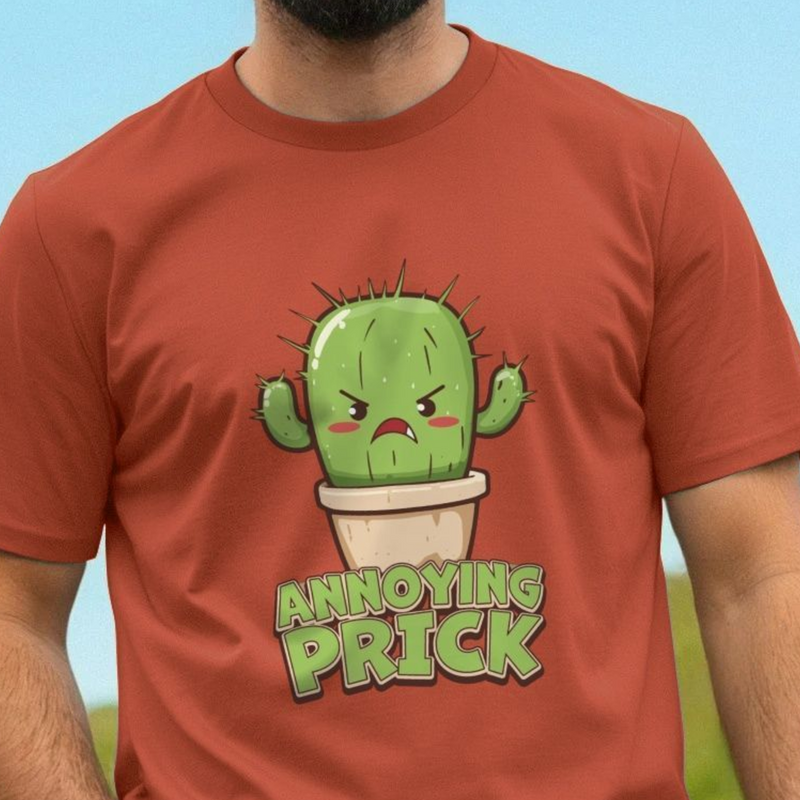 Red funny t-shirt with a cartoon cactus and 'Annoying Prick' slogan on a blurred natural background
