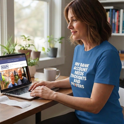 Woman in a blue t-shirt using a laptop at a desk with plants and books in the background