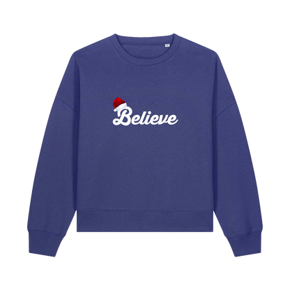 blue christmas sweater with the slogan 'believe' and a santa hat on top of the b