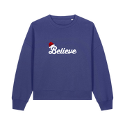 blue christmas sweater with the slogan 'believe' and a santa hat on top of the b