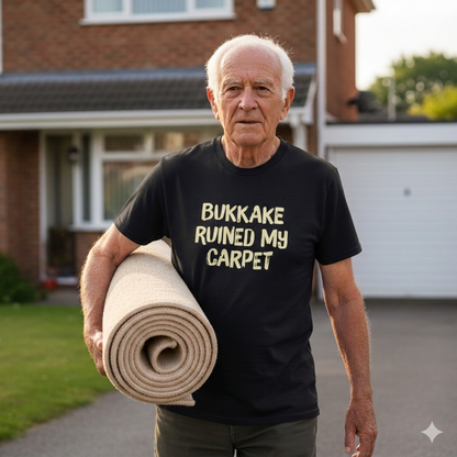 Man holding a rolled-up carpet with text on his shirt in front of a house.