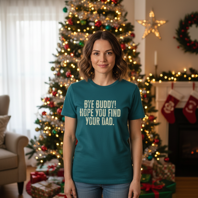 woman wearing a teal t-shirt with the text 'bye buddy i hope your find your dad', whilst stood in front of a christmas tree