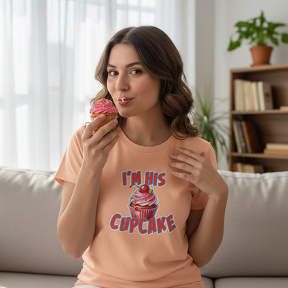 woman sat eating a cupcake, wearing a peach t-shirt with a cupcake graphic on