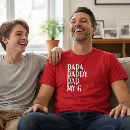 Man wearing a red t-shirt with 'Dada. Daddy. Dad. My G.' text, sitting on a couch with a young boy.