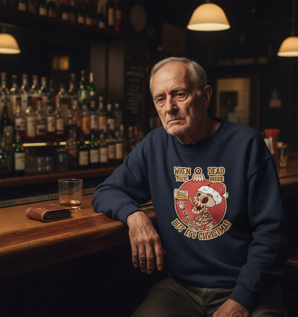 Man sitting at a bar wearing a funny christmas sweater with a Christmas design, surrounded by bottles and a glass.