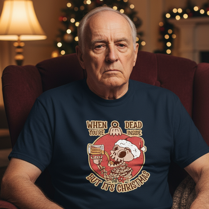 Man wearing a navy blue t-shirt with a Christmas-themed graphic sitting in a room decorated for Christmas.