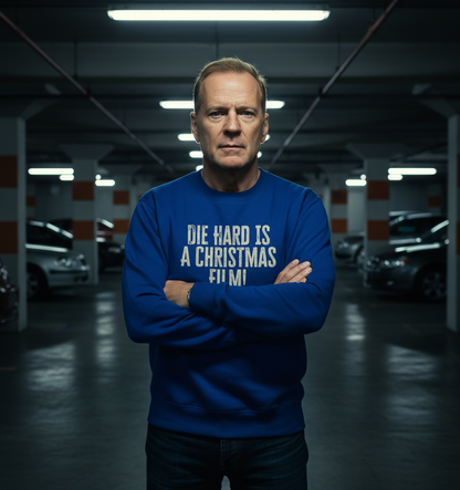 Man wearing a blue Christmas sweatshirt with the text "Die Hard is a Christmas film" in a parking garage