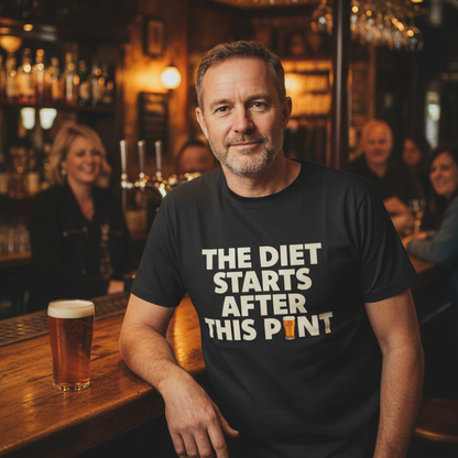 Man wearing a black t-shirt with a humorous print, sitting at a bar with a beer.