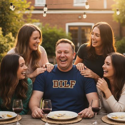 A group of people laughing around an outdoor table. A man in a "DILF" shirt sits at the center. Warm lighting and string lights create a joyful atmosphere.
