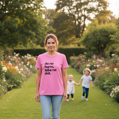 Woman wearing a pink t-shirt with the slogan 'do no harm take no shit' in a garden with two children.
