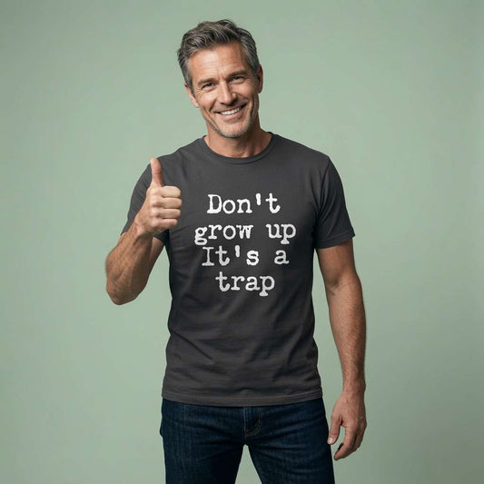 Smiling man giving thumbs up in black Don’t Grow Up It’s a Trap t-shirt, fun age-related slogan
