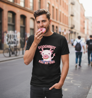 Man wearing a black t-shirt with a doughnut graphic and text, standing on a city street.