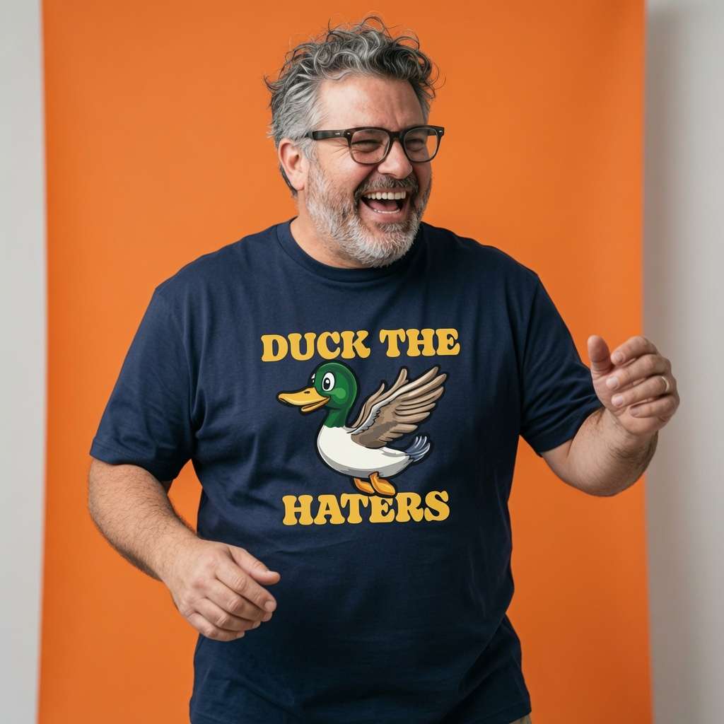 Man laughing with both hands raised while wearing a navy Duck The Haters t-shirt featuring a cartoon mallard duck, funny mens duck pun graphic shirt full of pure attitude