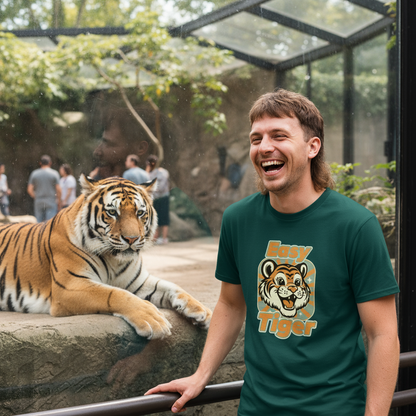 Man wearing a 'Easy Tiger' t-shirt standing next to a tiger in a zoo enclosure.