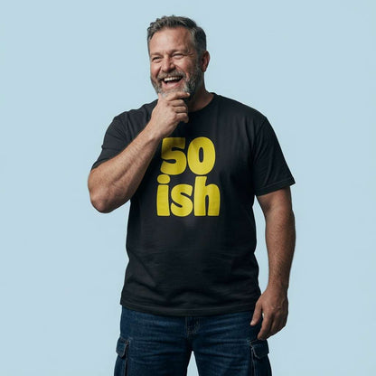 Grey-haired man laughing with hand on chin in black 50 ish tee, mens fun cheeky 50 year slogan