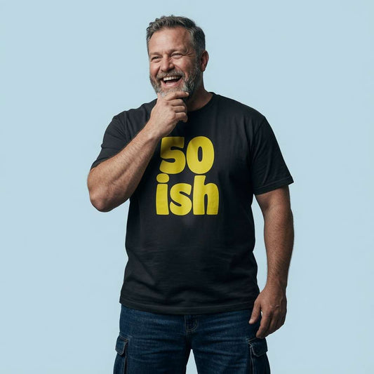 Grey-haired man laughing with hand on chin in black 50 ish tee, mens fun cheeky 50 year slogan