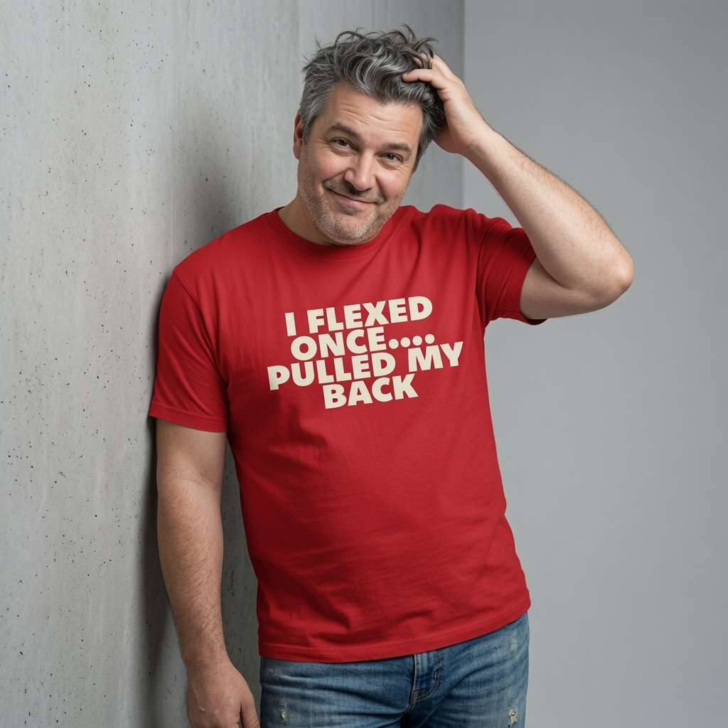 Grey-haired man smiling with hand in hair in red I Flexed Once Pulled My Back t-shirt, funny witty mens sarcastic slogan
