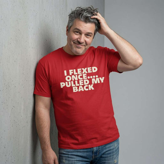 Grey-haired man smiling with hand in hair in red I Flexed Once Pulled My Back t-shirt, funny witty mens sarcastic slogan