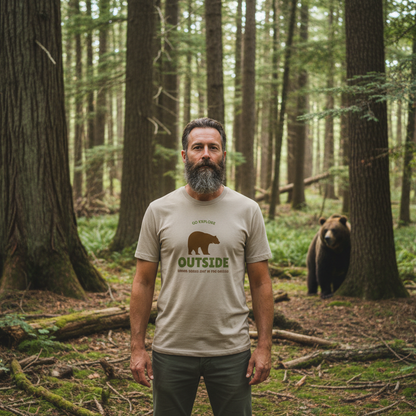 Man wearing a t-shirt with a bear graphic and 'Outside' text in a forest setting.