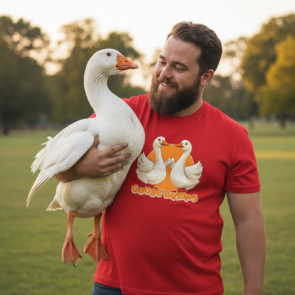 Man holding a white goose wearing a red t-shirt with a goose graphic in an outdoor setting