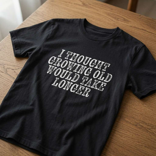 Black I Thought Growing Old Would Take Longer t-shirt on wood, mens funny witty slogan (women’s cut)
