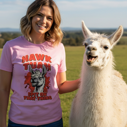 Woman wearing a pink t-shirt with a graphic design of a llama and text, standing next to a llama in an outdoor setting.