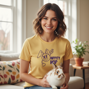 Woman wearing a yellow t-shirt with a bunny design, holding a rabbit indoors.