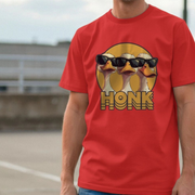 Red funny goose t-shirt with a graphic of geese wearing sunglasses and the word 'Honk' on a blurred background.