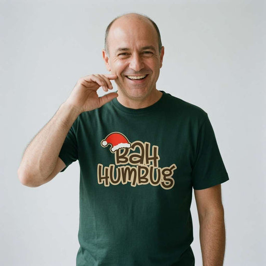 Balding man smiling and touching face in green Bah Humbug t-shirt with Santa hat graphic, fun mens witty christmas slogan