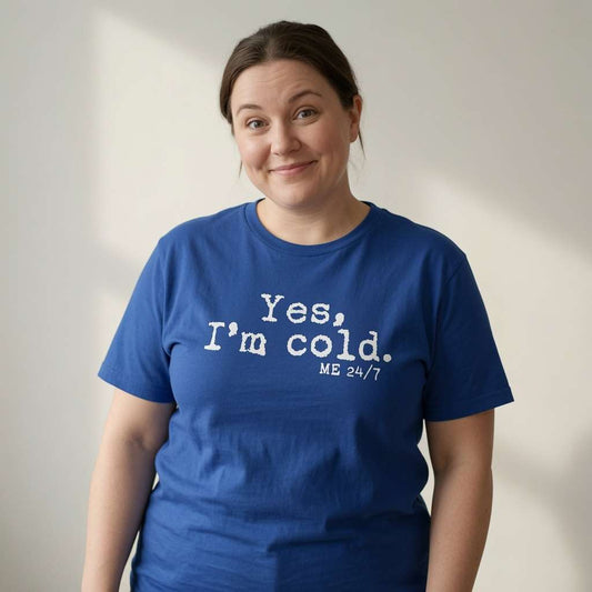 Woman with slight smile in blue Yes, I’m Cold. ME 24/7 t-shirt, witty slogan