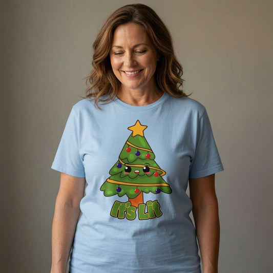 Woman looking down smiling in light blue It’s Lit tee with cartoon Christmas tree design, ladies funny kawaii xmas tree