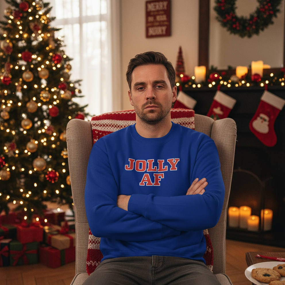 Man wearing a blue sweater with 'Jolly AF' text in a festive room with Christmas decorations.