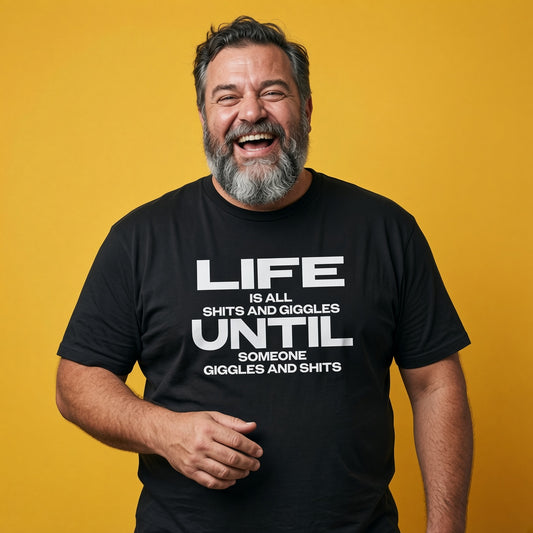 Man laughing while wearing a black Life Is All Shits And Giggles Until Someone Giggles And Shits t-shirt, funny mens witty relatable slogan design full of pure attitude