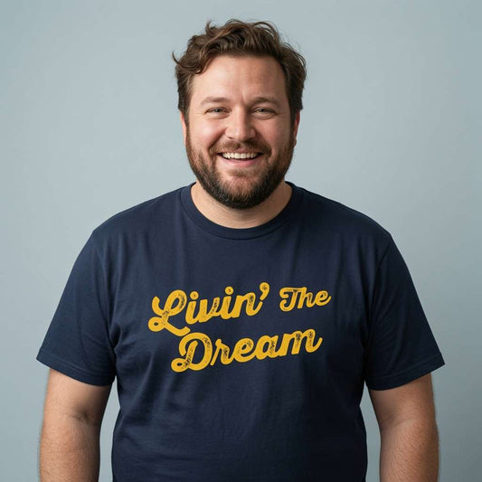 Bearded man smiling in navy Livin’ The Dream t-shirt, mens fun relatable slogan