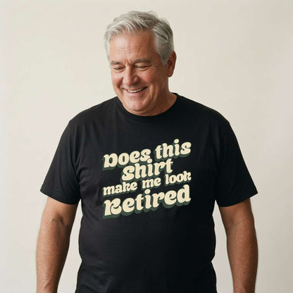 Grey-haired man smiling looking down in black Does This Shirt Make Me Look Retired tee, cheeky fun retirement slogan