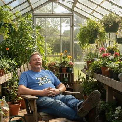 Man sitting in a greenhouse surrounded by plants wearing a blue shirt with text.