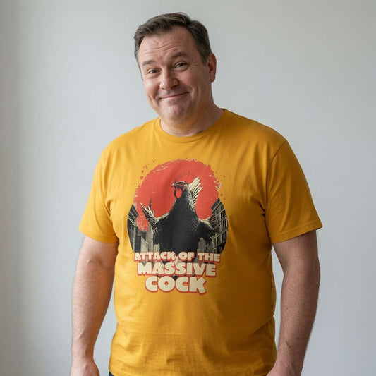 Man with slight smile looking to the side in yellow Attack of the Massive Cock t-shirt featuring giant rooster graphic, fun cheeky mens rude animal pun