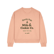 peach xmas sweater with the slogan 'north pole milk and cookie co'