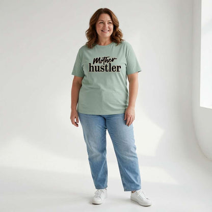 Woman smiling standing in green Mother Hustler tee, fun relatable busy mum slogan
