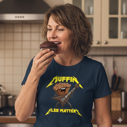 Woman wearing a blue t-shirt with a muffin-themed graphic eating a chocolate cupcake in a kitchen.