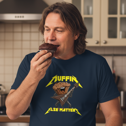 Man eating a chocolate muffin wearing a t-shirt with a graphic design in a kitchen.