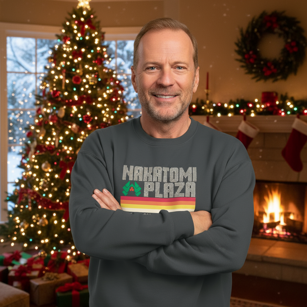 Man wearing a 'Nakatomi Plaza' sweatshirt in a festive room with Christmas tree and fireplace.