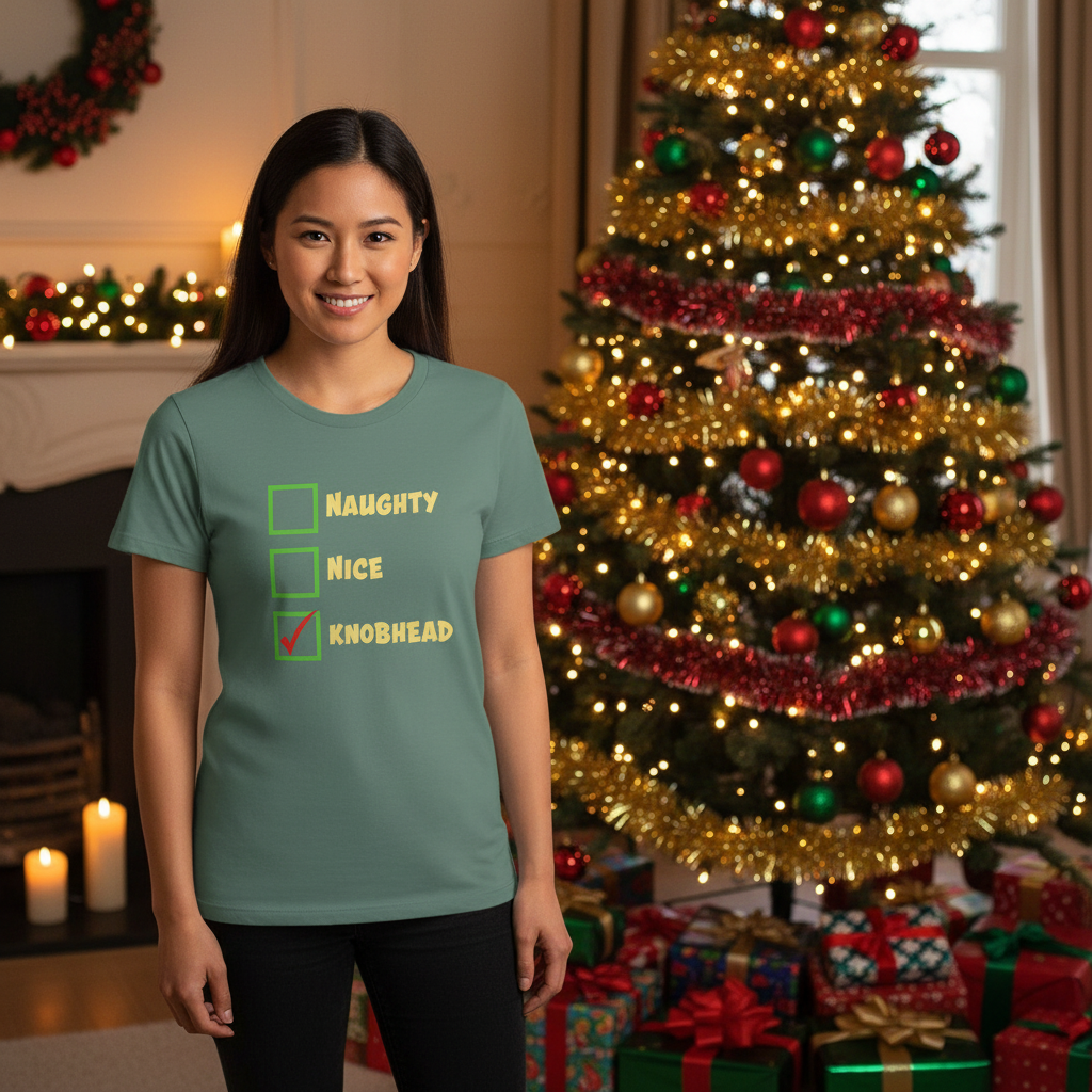 Woman wearing a t-shirt with Christmas-themed text in front of a decorated Christmas tree and presents.