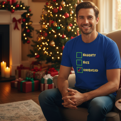 Man wearing a blue t-shirt with Christmas-themed text in a festive living room.